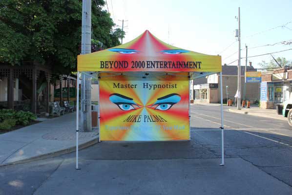 Hamilton Hypnosis, DJ Hamilton, Beyond 2000 Entertainments Canopy with back wall. Very colorful canopy with hypnotic eyes on all four side of the roof and Beyond 2000 Entertainment written on the canopy edges. Back drop has large hypnotic eyes. With the words Master hypnotist above the eyes. Below the eyes Mike Palma Experience the power of your mind. Taken in Hamilton Ontario